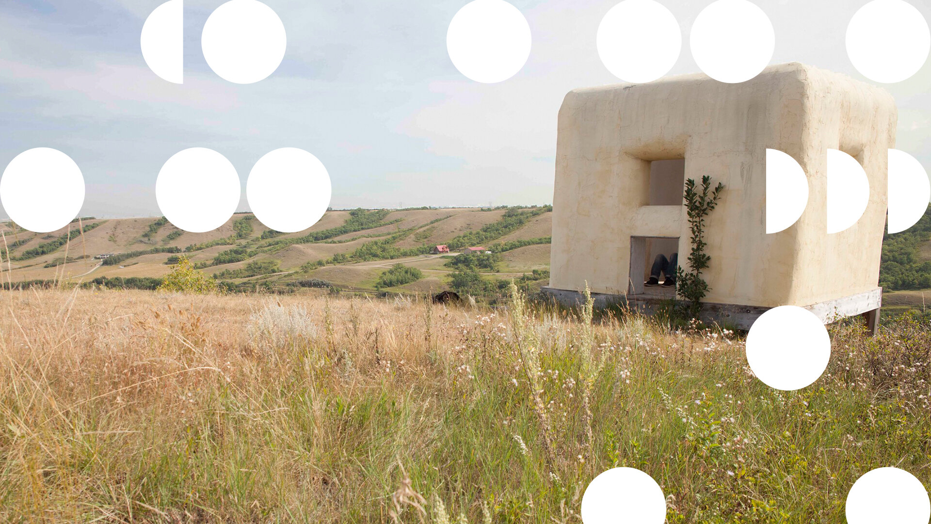 A pale rendered structure standing alone in a wide grass field, overlaid with scattered white circles.