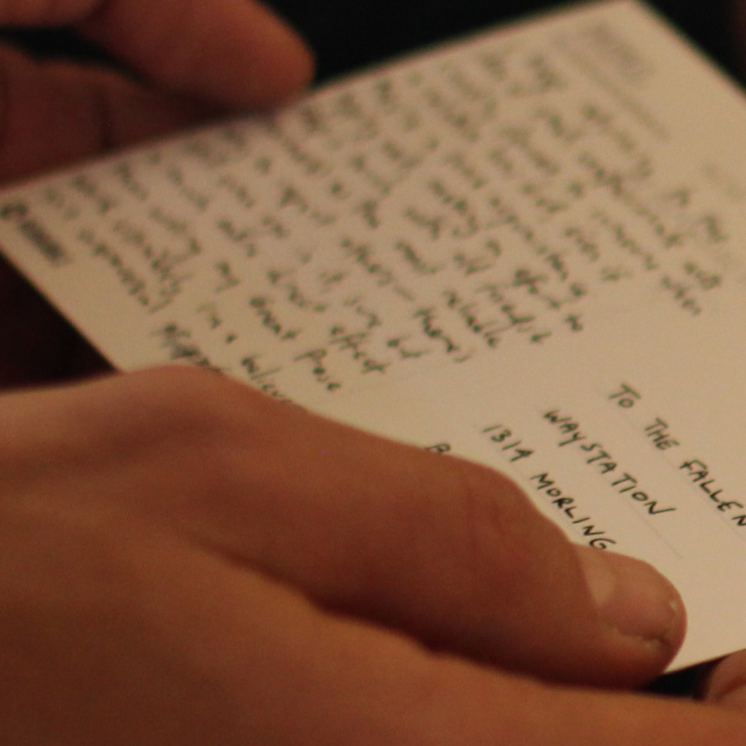 A hand holding a small handwritten card.