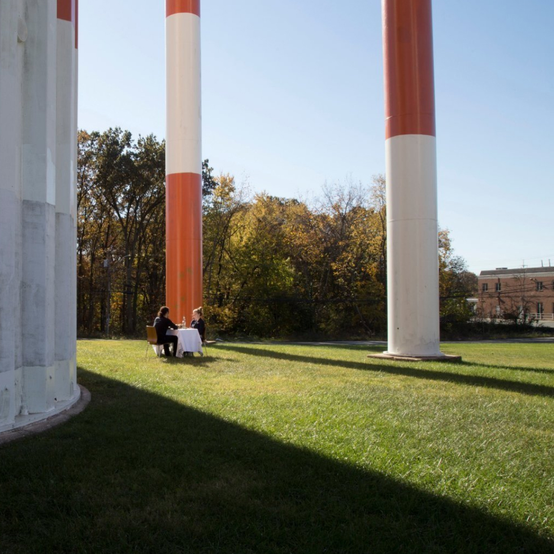 Two tall striped columns standing in a park, with a small group gathered at their base.